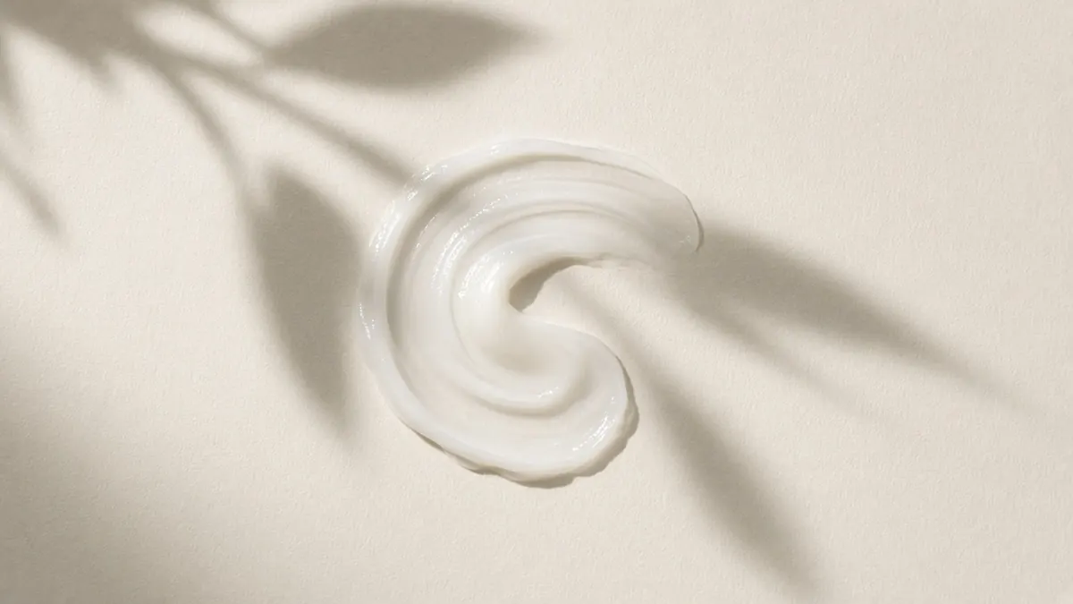 A swirl of lightweight white lotion under soft leaf shadows