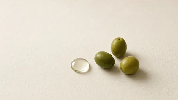 Green olives beside a clear oil droplet