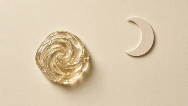 A glossy swirl of clear petrolatum beside a paper crescent moon, for overnight use
